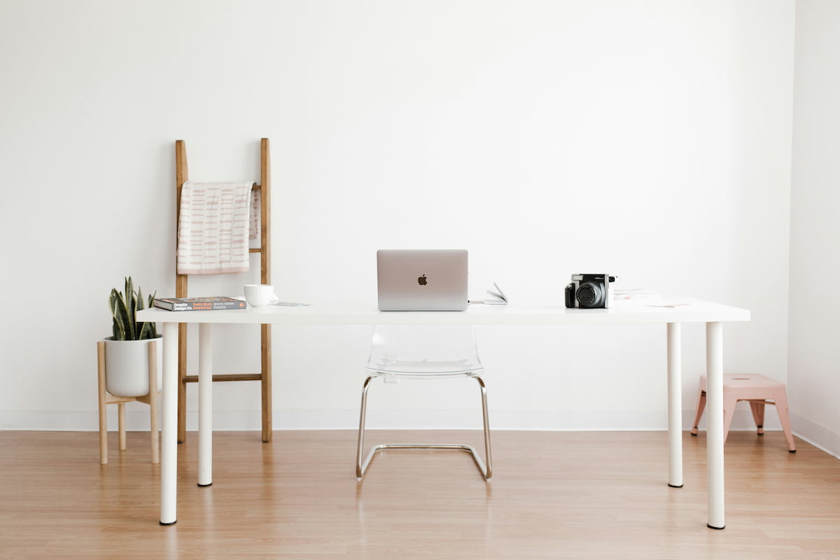 A bright, uncluttered workspace with a laptop open on a white desk